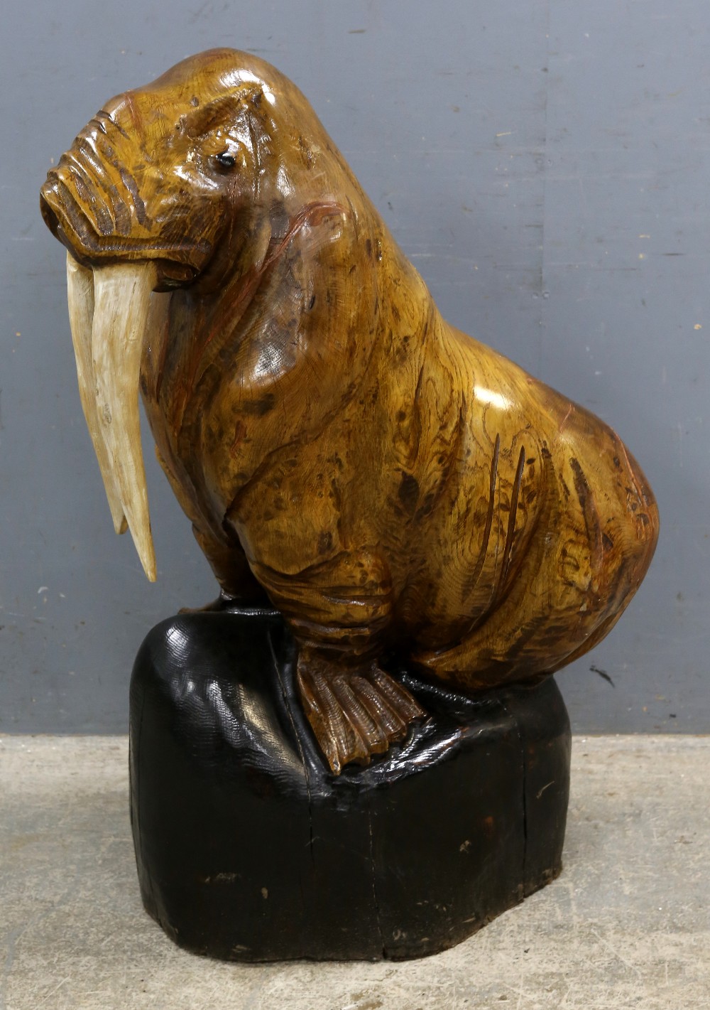 A large wooden carving of a walrus, H.114cm Large cracks to body and base. Evidence of repair to one