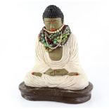 Painted terracotta Buddha wearing costume jewellery necklaces, on concrete base, height including