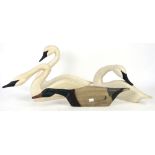 Three hand-painted and carved wooden swans, indistinctly signed to bases, H.32cm W.42cm (largest),