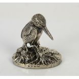 Silver model of a Kingfisher bird sat on a tree branch and vegetation