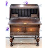 18th century style oak fall front bureau over 2 drawers on carved supports. Break to front legs