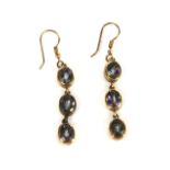 A pair of drop earrings, each set with three oval cut mystic topaz, in rub over setting, French