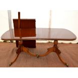 Mahogany extending dining table, with twin pedestal supports on splayed legs and castors, with extra