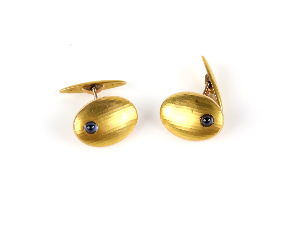 20th century oval cufflinks, each set with an off-centre cabochon sapphire to a panelled design,