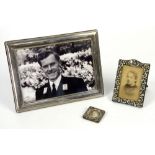 Three silver-mounted photograph frames including a Victorian frame with scrolling leaves, by