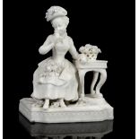 Parian ware figural group modelled as a woman in 18th century dress seated beside a table with