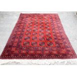 Bokhara red ground carpet, repeating gul motifs on a red ground within stylised floral borders,