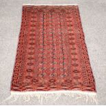 Bokhara rug, with repeating gul motifs on a red ground, within stylised floral borders, 178 x 111cm