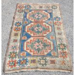 Kazak rug with three central medallions on a light blue ground with floral motifs, contained