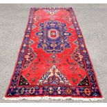 Collection of three rugs comprising a Russian rug with repeating floral motifs on a red ground