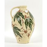 C H Brannam, Barnstaple studio pottery jug with green leaves and brown berries decoration on a cream