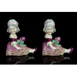 Porcelain bookends moulded as a girl seated, with pink frill skirt holding a posey (2)
