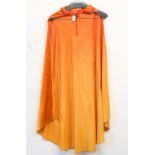 Two orange satin hooded capes with black horns used in movies such as Hellzapoppin, one with Western