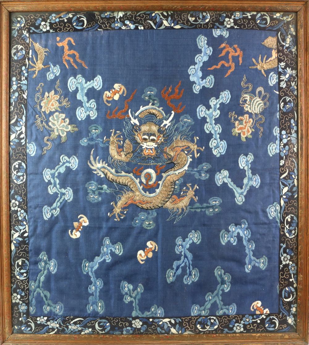 A framed Chinese textile of a coiled dragon, overall dimensions including frame about 65 x 58 cm;