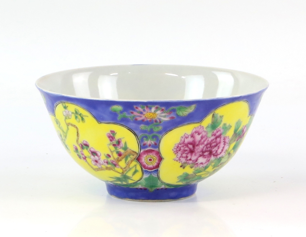 A famille rose bowl, decorated on a blue ground with panels of lotus, peony and prunus; the base