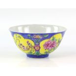 A famille rose bowl, decorated on a blue ground with panels of lotus, peony and prunus; the base