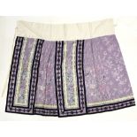 A Chinese textile skirt decorated with both vertical and horizontal blue lines beside designs of