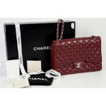Chanel “Maxi Classic” deep red flap bag in rare “soft caviar” leather with silver hardware,