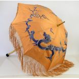 A Chinese parasol the apricot silk shade embroidered with a Dragon, tassel border, ivorine handle