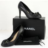 Black leather high heel Chanel shoes with typical leather camellia motif and crossed C’s logo.