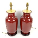 Pair of deep red table lamps on wooden base H38cm x W17cm.Neither lamp tested working. One lamp