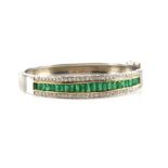 Emerald and diamond bangle, comprising a channel set line of graduated emerald cut emeralds,