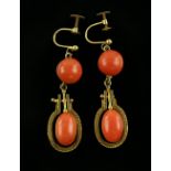 Pair of coral earrings, designed as an oval coral bead suspended in a gold surround, with wirework
