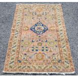 Persian style rug, central floral medallion and stylised floral motifs on a pink ground contained by