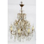 Gilt metal eight light chandelier with three tiers of drops and beads, scrolling arms, glass drops