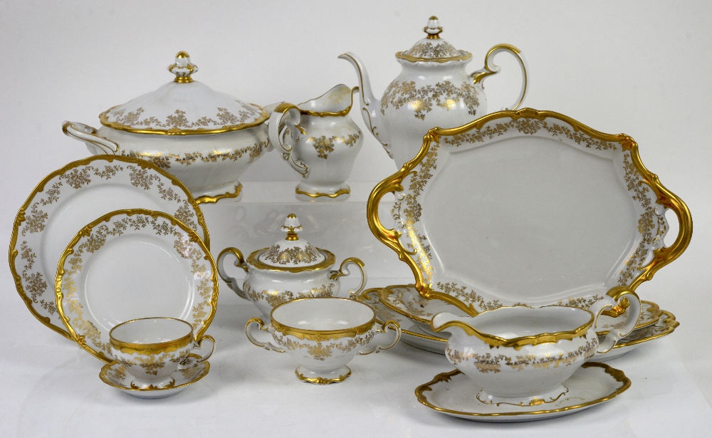 Weimar porcelain dinner service for 12, decorated in gilt with a band of scrolling leaves and