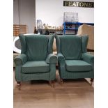 A PAIR OF GREEN FABRIC WING BACK CHAIRS ON BRASS CASTERS