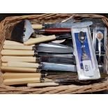 TWIN HANDLED WICKER BASKET CONTAINING MISCELLANEOUS CUTLERY AND CRESTED SPOONS