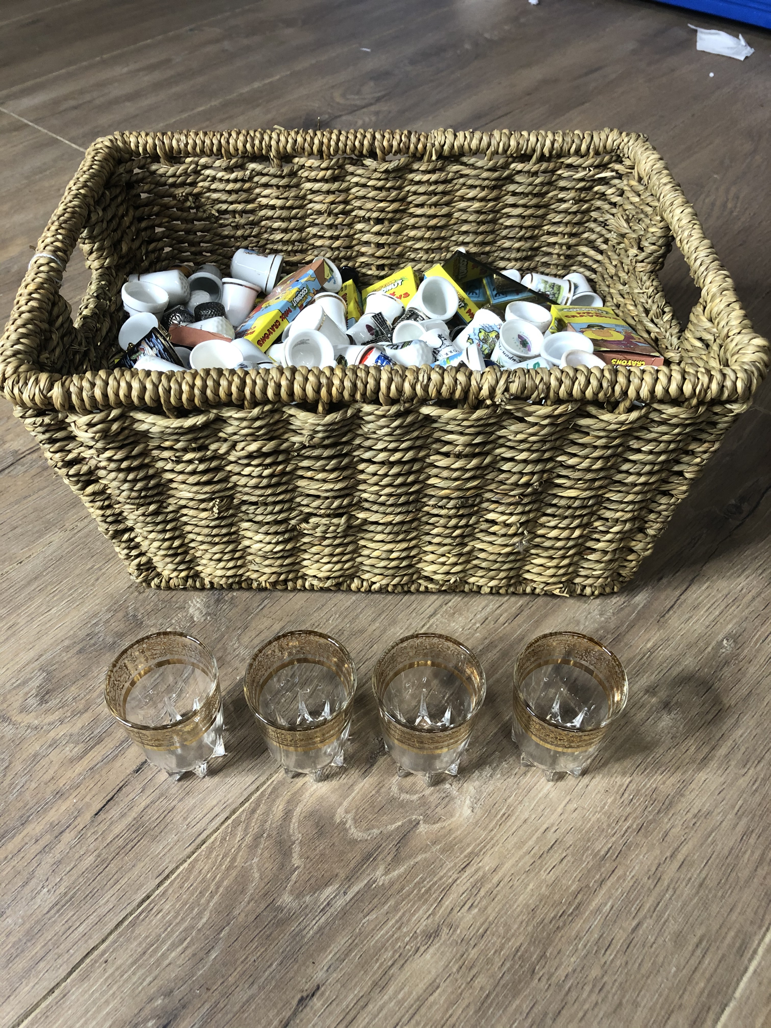A WICKER BASKET CONTAINING A LARGE AMOUNT OF THIMBLES AND MATCHES