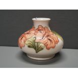 A MOORECROFT SQUAT FORM VASE DECORATED WITH THE HIBISCUS PATTERN ON A CREAM BACKGROUND