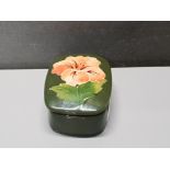 A MOORECROFT HIBISCUS PATTERNED TRINKET BOX ON A GREEN BACKGROUND 7CM BY 6CM BY 3.5CM