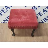 A RED BUTTONED FOOTSTOOL WITH FRILLED EDGES AND METAL STUDDING
