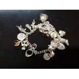 A SILVER CHARM BRACELET TO INCLUDE SOME SPINNING AND MOVING CHARMS 64.1G GROSS