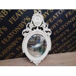 A BAROQUE STYLE WHITE PAINTED BEVELLED OVAL WALL MIRROR IN ORNATE FRAME 111 X 58CM