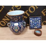 A FRAMED IZNIK TILE AND MOUNTED ASHTRAY TOGETHER WITH AN IZNIK STYLE THREE HANDLED VASE (CRACKS)