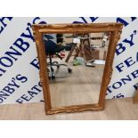 A MODERN BEVELLED WALL MIRROR IN GOLD COLOURED FRAME 70 X 50CM