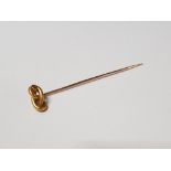 A YELLOW METAL STICK PIN WITH GILT METAL TOP INDISTINCT STAMP TO PIN 1.8G GROSS