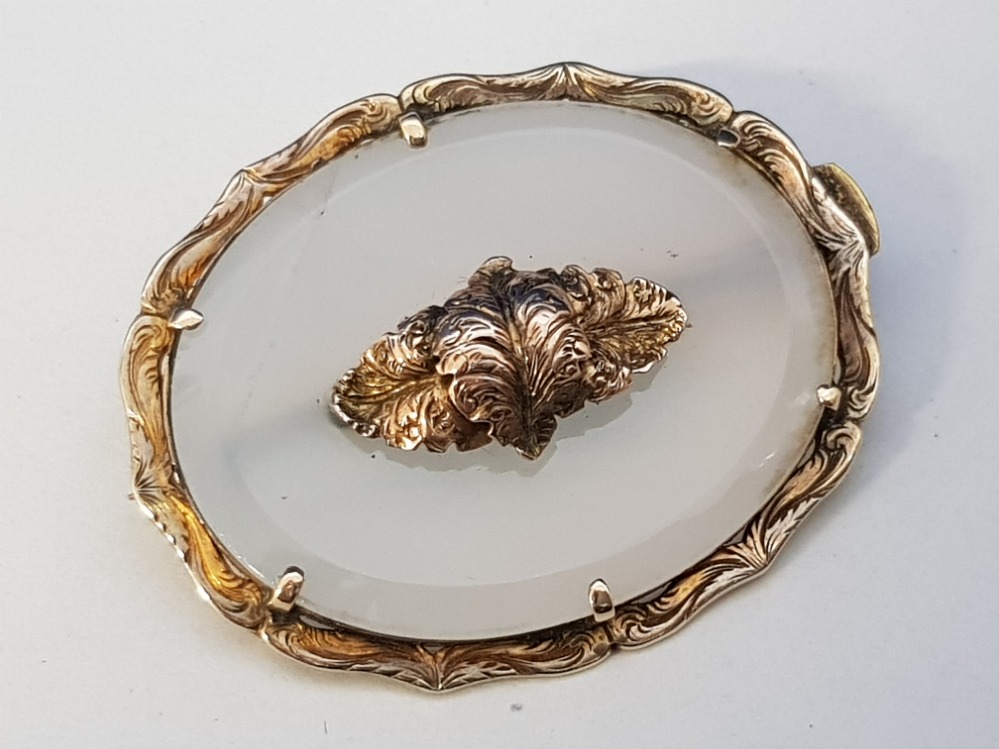 A GILT METAL AND HARDSTONE BROOCH WITH CENTRAL SCROLLING CARTOUCHE