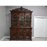 A 19TH/EARLY 20TH CENTURY CONTINENTAL HEAVILY CARVED OAK SIDEBOARD WITH STAINED GLASS PANEL DOORS