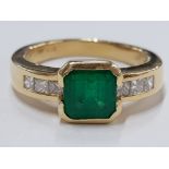 AN 18CT YELLOW GOLD OCTAGON STEP CUT COLUMBIAN EMERALD RING WITH DIAMOND SHOULDERS, 8.2G SIZE P1/
