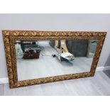 A MODERN BEVELLED WALL MIRROR IN GOLD COLOURED SWEPT FRAME 83 X 144CM