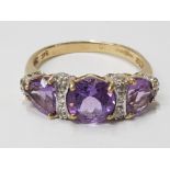 LADIES 9CT YELLOW GOLD PURPLE THREE STONE RING SET WITH A ROW OF ROUND CUT DIAMONDS BETWEEN EACH