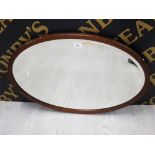 AN OVAL BEVELLED WALL MIRROR WITH STAINED WOOD FRAME 74.5 X 49.5CM