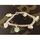 A WHITE METAL CHARM BRACELET WITH VARIOUS SILVER GRADED CHARMS 19.2G GROSS