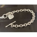 A SILVER LINK BRACELET WITH HEART SHAPED CHARM AND T BAR CLASP 21CM LONG 24.1G