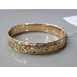 1/5 9CT GOLD BANGLE WITH METAL CORE FERN CUT ETCHED TO ONE SIDE AND HAVING A SAFETY CHAIN 21.7G